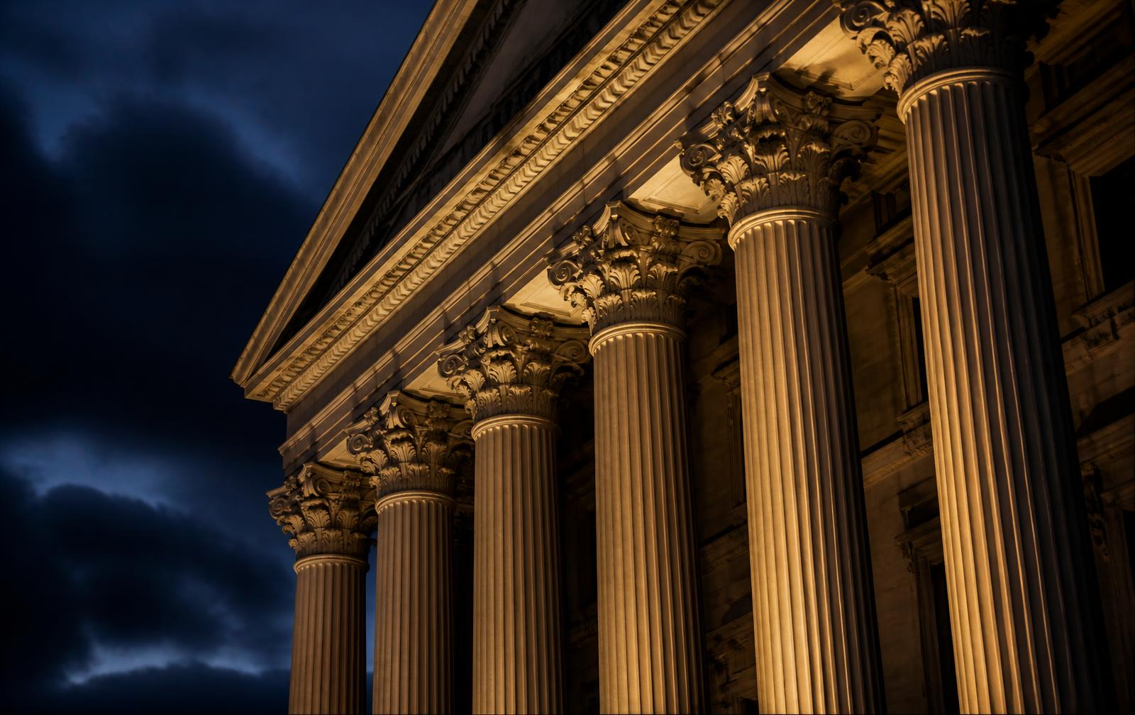 Stone columns of a federal government building lit at dusk